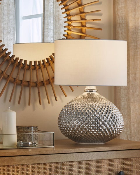 Dekorative Tischlampe mit Lampenschirm auf einem Beistelltisch neben einer Kerze und einem Spiegel