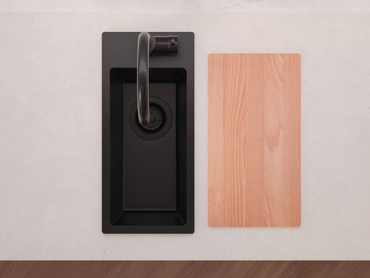 Schwarze Einbauspüle mit schwarzer Armatur und Holzschneidebrett auf heller Arbeitsplatte in der Draufsicht.