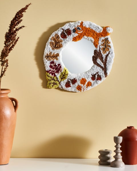 Dekorativer Spiegel mit Fuchs- und Herbstmotiven, umrahmt von weichem Material, hängt an einer Wand.