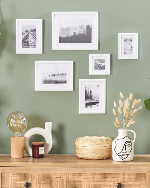 Dekorative Wand mit Bilderrahmen und verschiedenen Dekorationsgegenständen auf einer Kommode