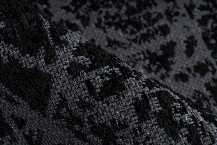 Nahaufnahme eines strukturierten Webteppichs mit dunklem Muster.