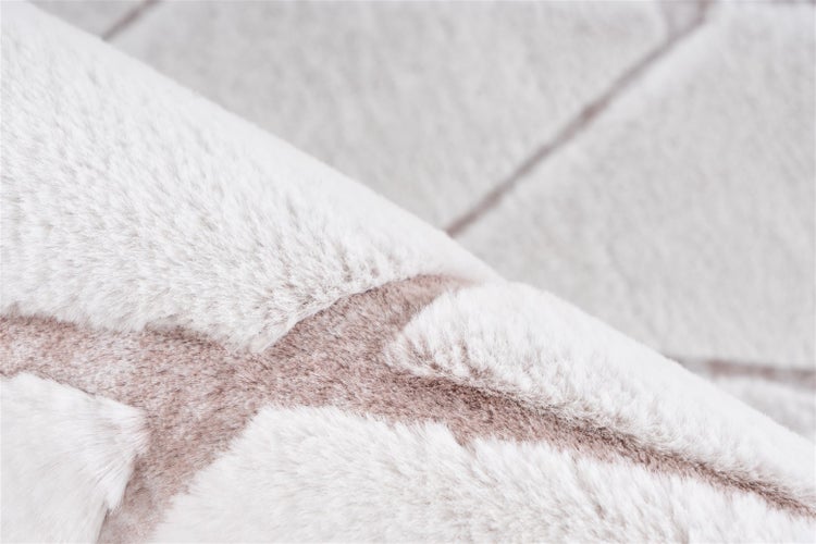 Nahaufnahme eines weichen Kunstfellteppichs mit geometrischem Muster und dicker Florhöhe.