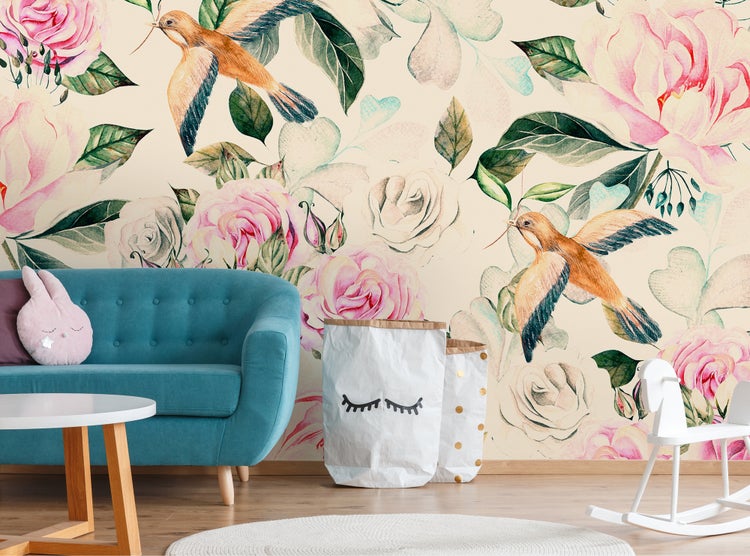 Helle Kinderzimmereinrichtung mit Vliestapete mit Blumen- und Vogelmotiv, blauem Sofa, weißem Schaukelpferd und Papier-Aufbewahrungssäcken.