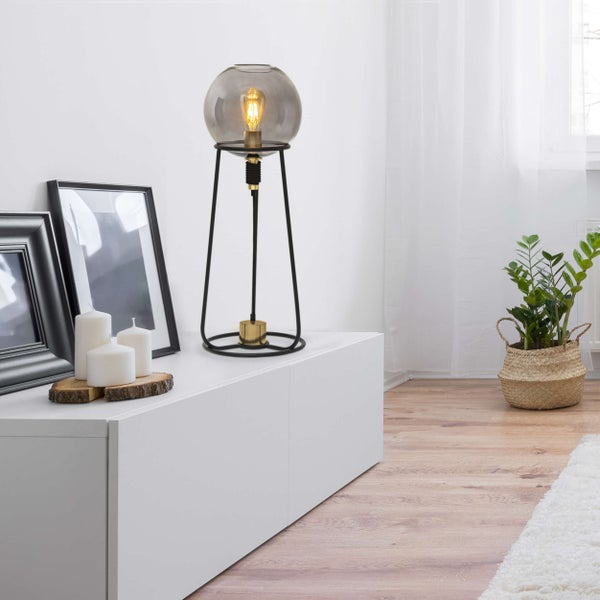 Innenaufnahme eines Wohnzimmers mit einer Kugel-Tischleuchte auf einem Sideboard, neben Kerzen und Bilderrahmen.