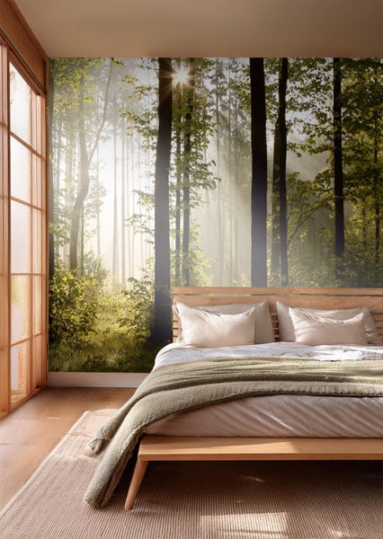 Schlafzimmer mit Fototapete mit Waldmotiv, Bett und Teppich.