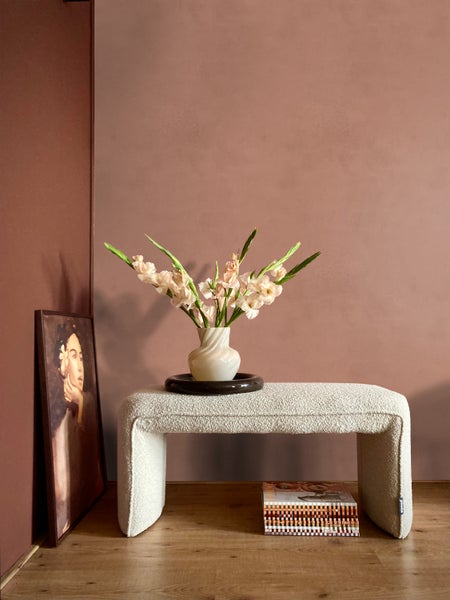 Innenraumszene mit gepolsterter Bank, Blumen und Gemälde