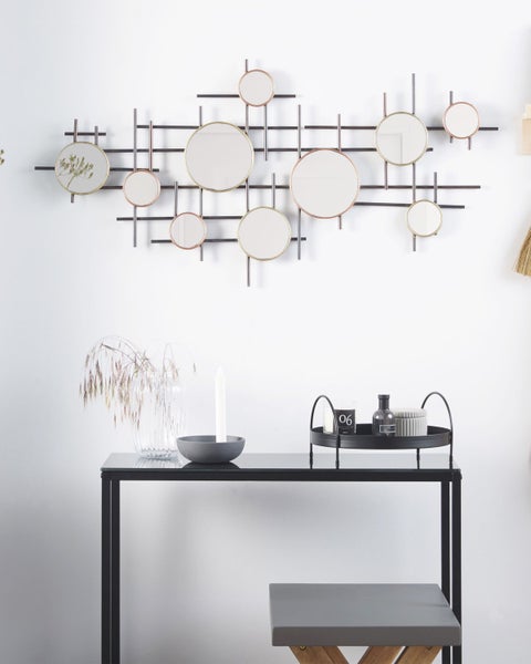 Dekoratives Wandobjekt mit Spiegeln über einem Konsolentisch mit Dekorationen.
