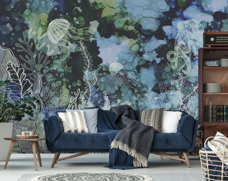 Fototapete mit Unterwassermotiv und weißen Illustrationen von Meerestieren hinter einem blauen Sofa mit Kissen in einem modernen Wohnzimmer.