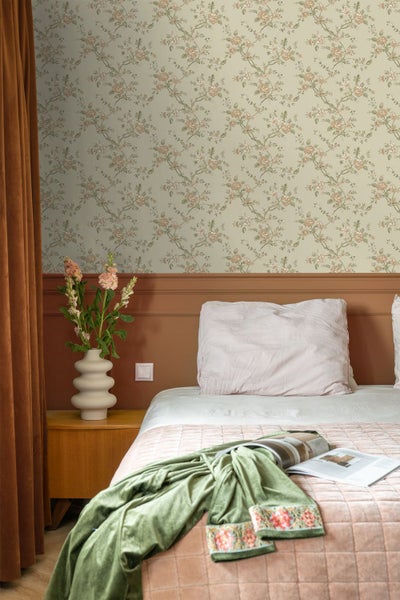 Schlafzimmer mit floraler Tapete über einer Wandvertäfelung, einem Bett, einem Nachttisch aus Holz und einer Vase mit Blumen.