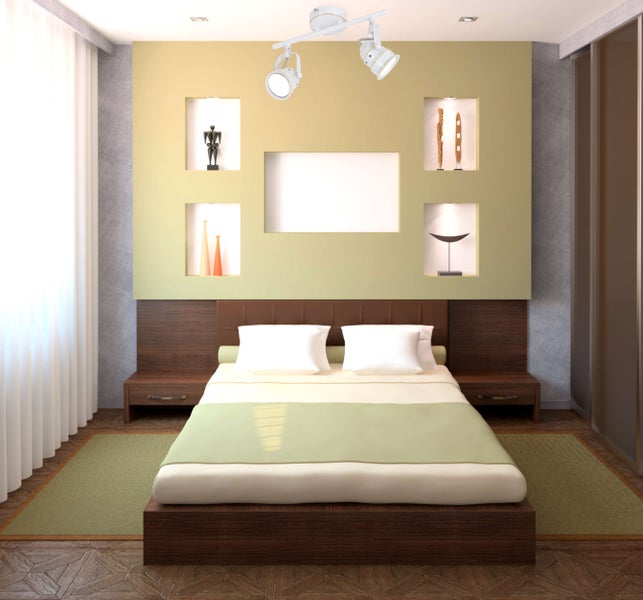 Schlafzimmer mit Bett, Nachttischen und Wandnischen mit dekorativen Elementen