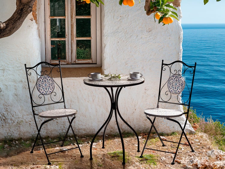 Gartensitzgruppe mit Tisch und zwei Stühlen auf einer Terrasse mit Meerblick