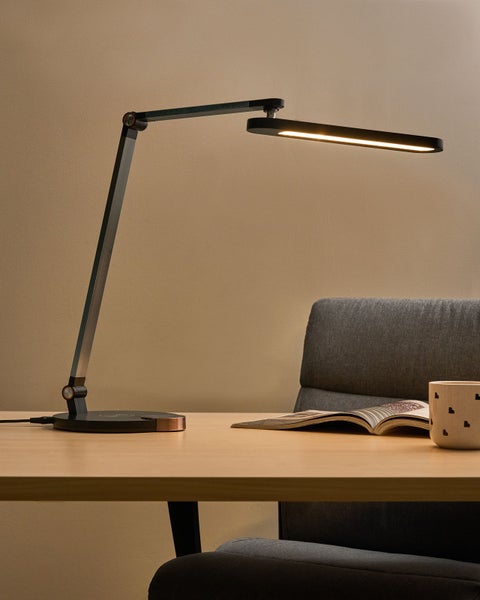 Schreibtischleuchte auf einem Schreibtisch mit Buch und Tasse