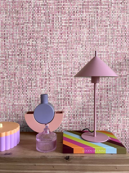 Dekorative Szene mit Tischleuchte, Buch und Vasen auf einem Tisch vor einer gemusterten Wand