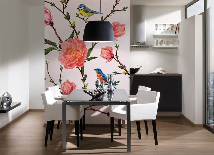 Modernes Esszimmer mit Fototapete mit rosa Blumen und Vögeln, dunklem Glastisch, weißen Stühlen und schwarzer Pendelleuchte.