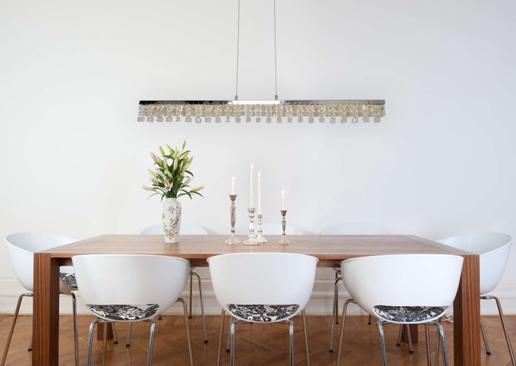 Esszimmer mit Esstisch, Stühlen, Blumenvase, Kerzenständern und Pendelleuchte