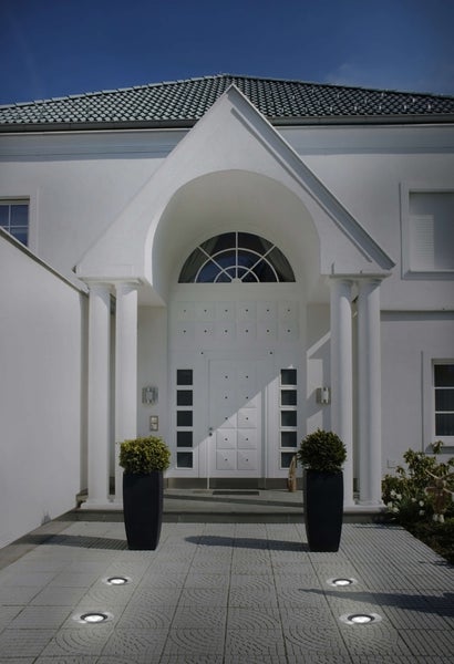 Eingang eines Hauses mit Wegbeleuchtung und Pflanzenkübeln