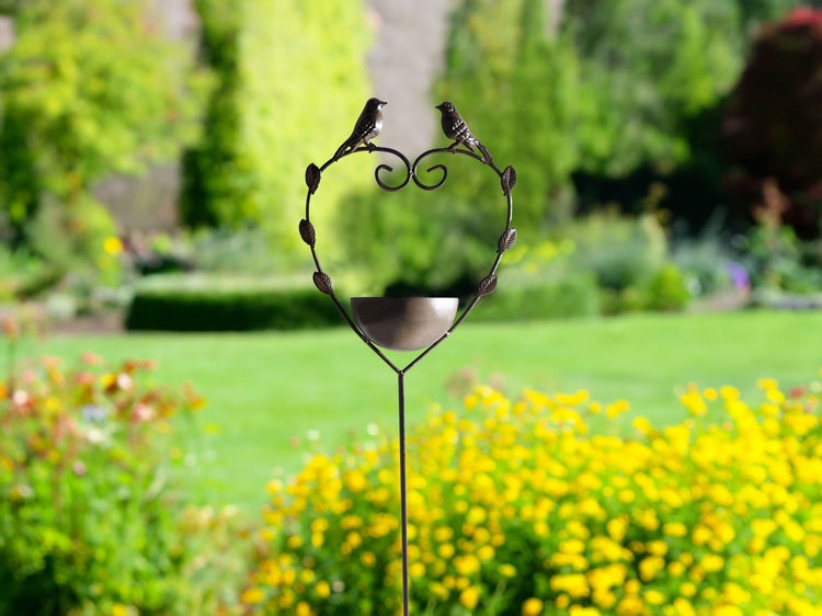 Dekorative Vogeltränke mit Herzdesign und zwei Vogelmotiven im Garten
