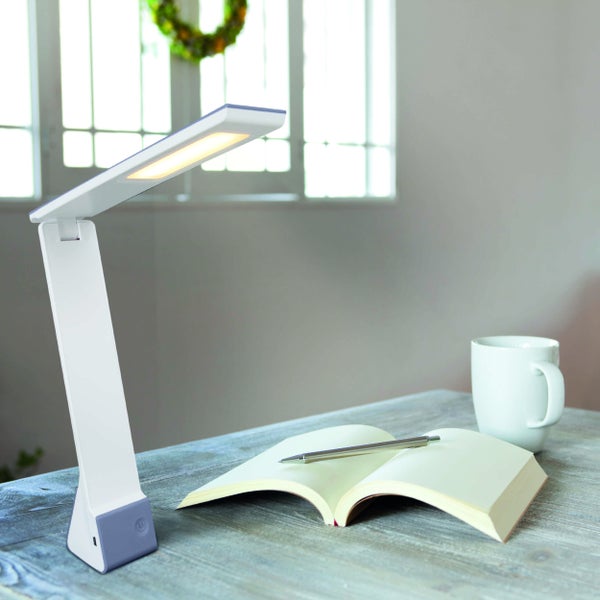 Schreibtischszene mit LED-Tischleuchte, Notizbuch, Stift und Tasse auf einem Tisch