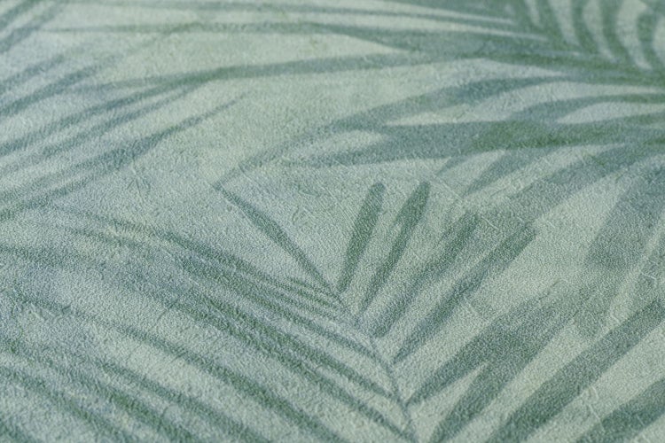 Frau mit gemusterter Tapete mit Palmenmotiven im Hintergrund