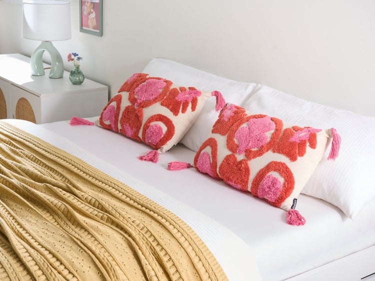 Dekoratives Bett mit zwei Kissen mit Quasten und geometrischen Mustern