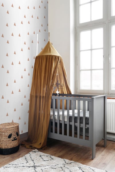 Graues Kinderbett mit Baldachin in einem hellen Raum