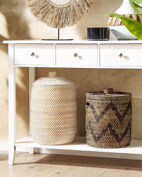 Weißer Konsolentisch mit drei Schubladen und zwei großen geflochtenen Aufbewahrungskörben mit Deckel auf der unteren Ablage in hellem Raum.