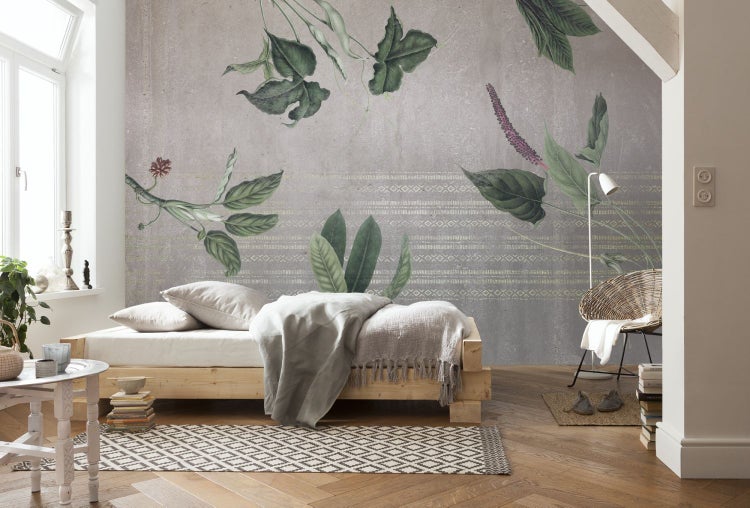 Schlafzimmer mit botanischer Mustertapete, Holzbett und Rattan-Sessel