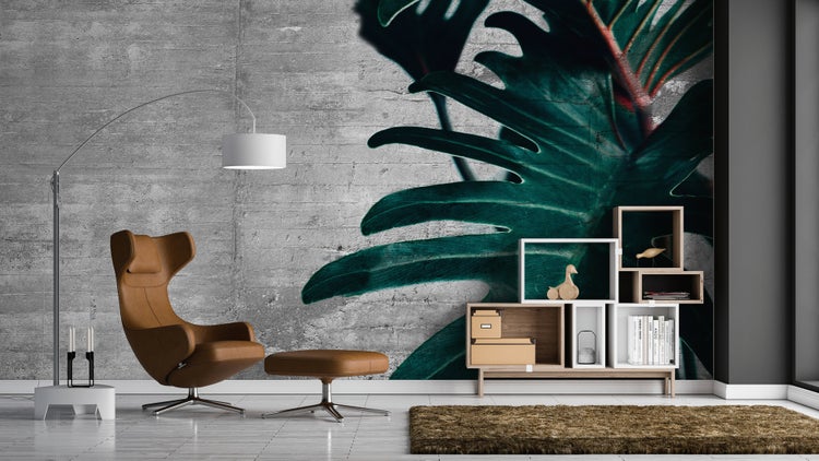Fototapete mit großem Blatt auf Wand in Betonoptik in einem modernen Wohnzimmer mit Sessel und Stehleuchte.
