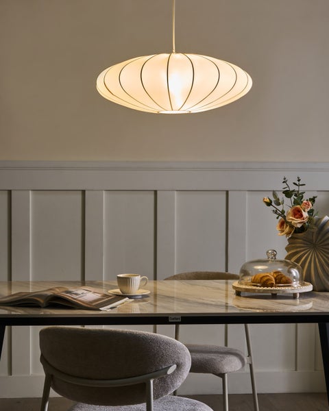 Ovalförmige Pendelleuchte über einem Esstisch mit Dekorationen