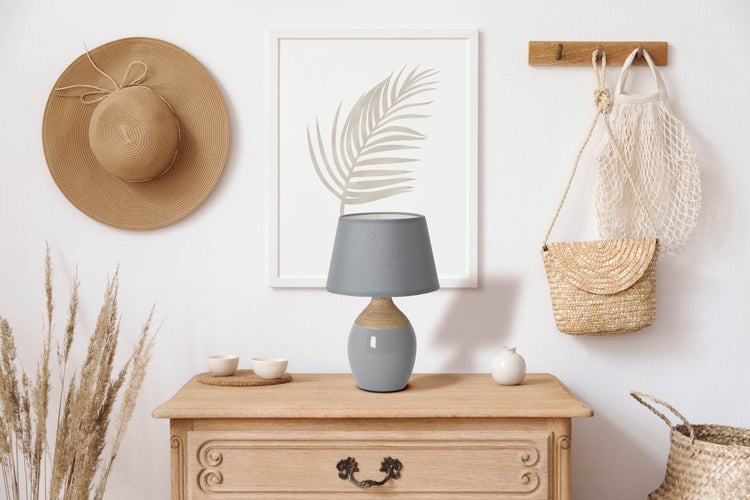 Dekorative Szene mit Kommode, Lampe, Hut und Wandbehang