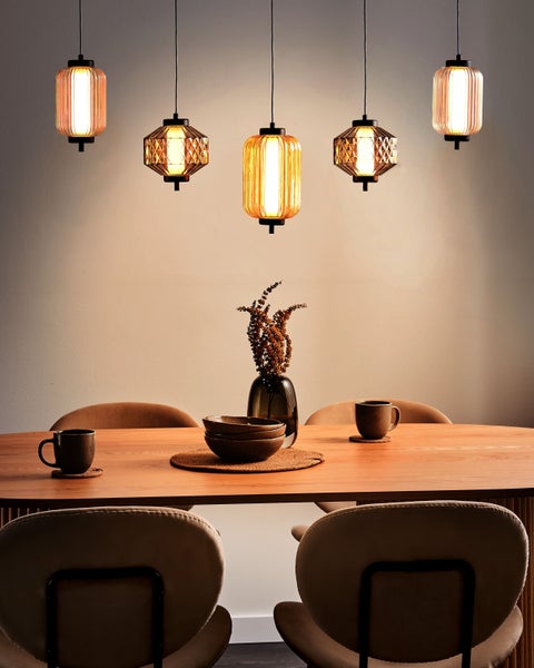 Esstisch-Szene mit fünf Pendelleuchten, Geschirr und Stühlen für eine helle und einladende Atmosphäre.