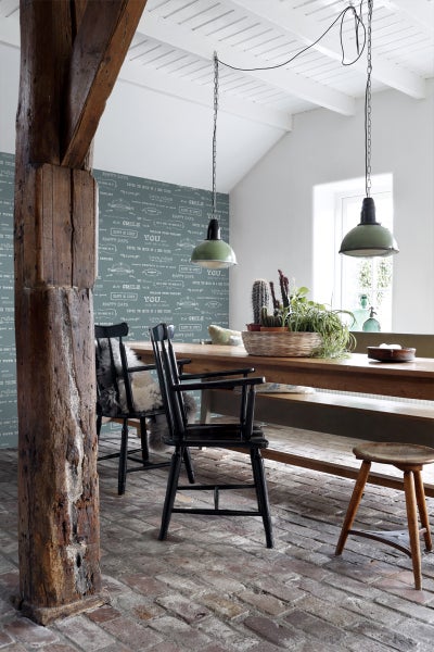 Helles Esszimmer mit Holztisch, Stühlen, Hängelampen und dekorativer Wandtapete für ein gemütliches Ambiente.