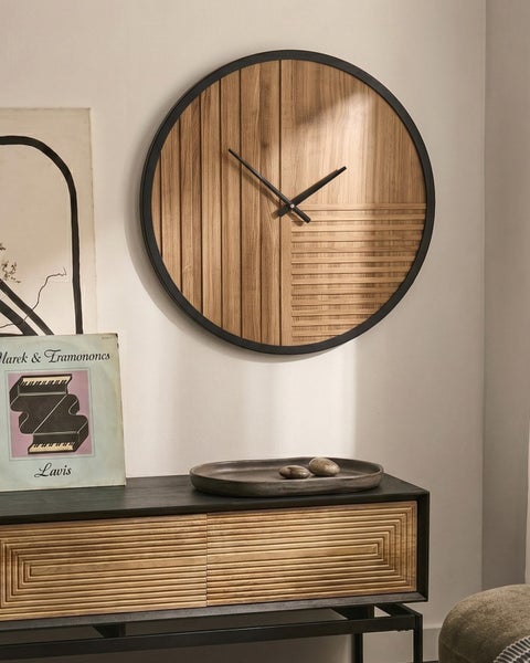 Moderne runde Wanduhr mit Holzfront und schwarzen Zeigern über einer Kommode mit Holzoptik in einem minimalistisch eingerichteten Raum