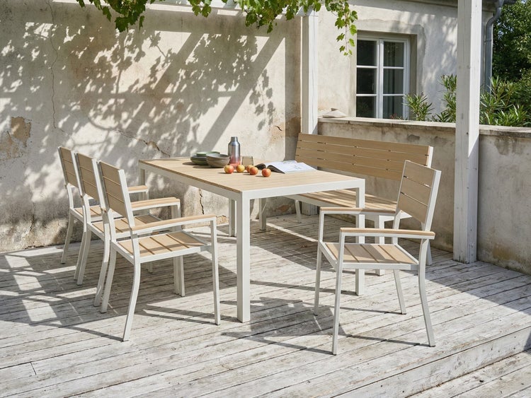 Gartenszene mit Esstisch, Stühlen und Bank aus Holz und Metall auf einer Terrasse.