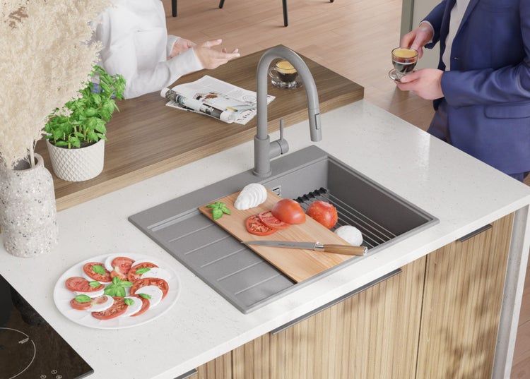 Küchenszene mit Spüle, Armatur, Schneidebrett, Lebensmitteln und zwei Personen