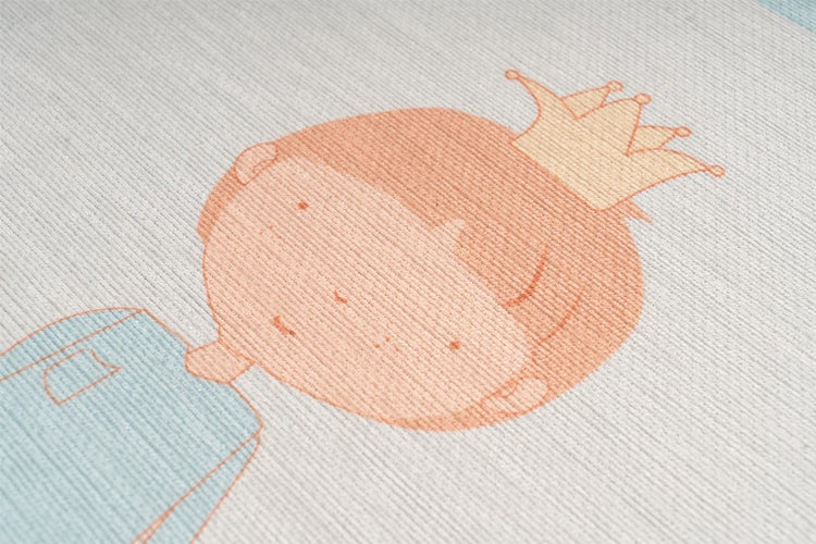 Strukturierte Textiloberfläche einer Kindertapete oder eines Teppichs mit aufgedrucktem Jungenmotiv mit Krone.