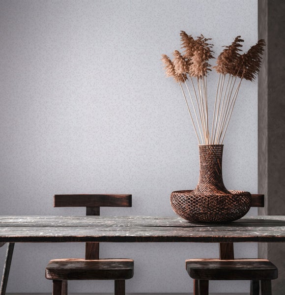 Dekoratives Arrangement mit Vase, Trockenblumen und Holzmöbeln vor einer gemusterten Wand