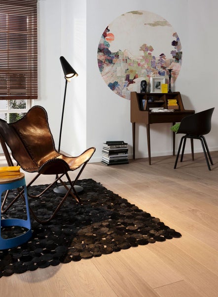Wohnzimmer mit Sessel, Schreibtisch, Stehlampe und Teppich