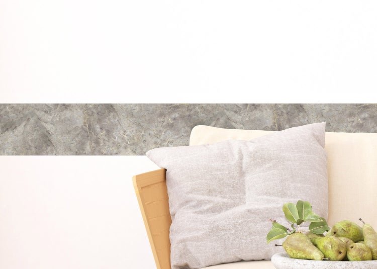 Selbstklebende Wandbordüre in Marmor-Optik hinter einem Sessel mit Kissen und Obstschale.
