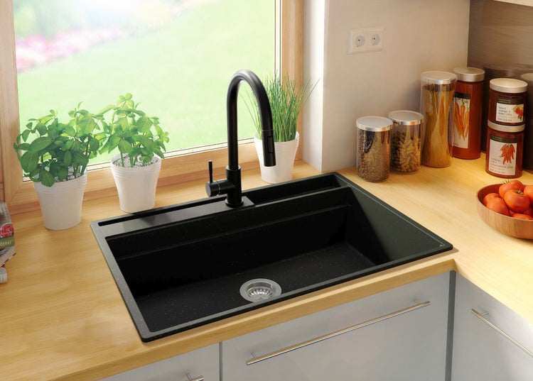 Spültisch aus Granit mit Wasserhahn in einer Küchenszene.