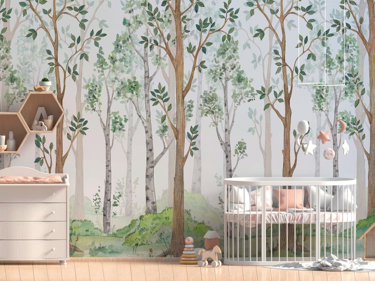 Fototapete mit Waldmotiv und Bäumen in einem hellen Kinderzimmer mit weißem Gitterbett und Wickelkommode.