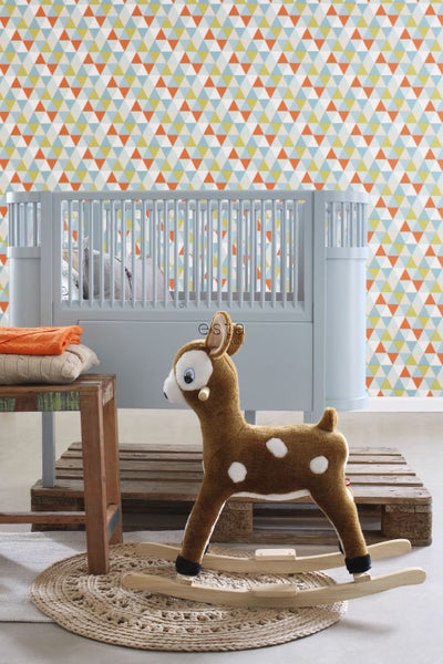 Dekoratives Kinderzimmer mit Babybett, Stofftier und farbenfroher Tapete mit Dreiecksmuster