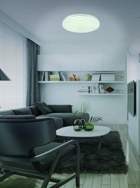 Wohnzimmer mit Sofa, Sessel, Couchtisch, Regalen und Deckenleuchte