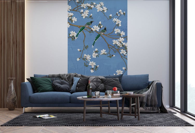 Wohnzimmer mit blauem Sofa, Couchtischen und Wandbild mit Blütenmotiven