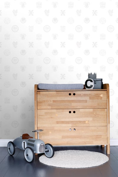 Kinderzimmer mit Wickelkommode aus Holz, Spielzeugauto und rundem Teppich