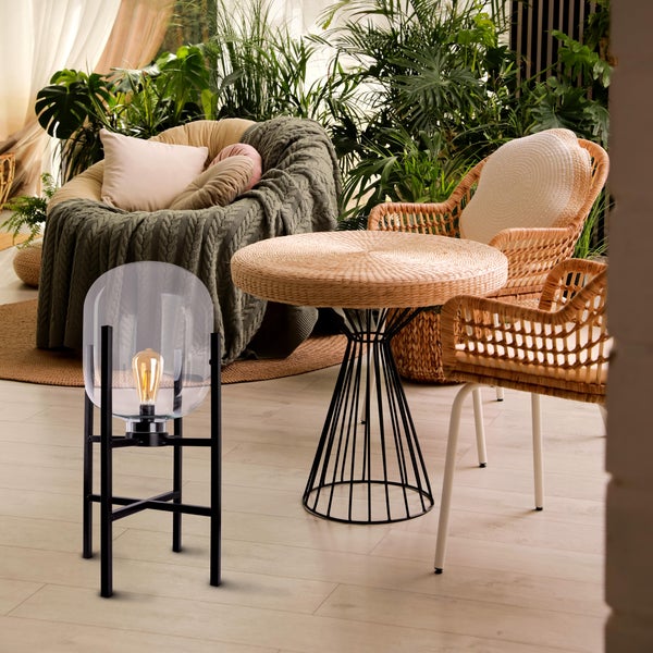 Wohnzimmer mit Korbsesseln, Tisch und Stehlampe mit Glaskolben.
