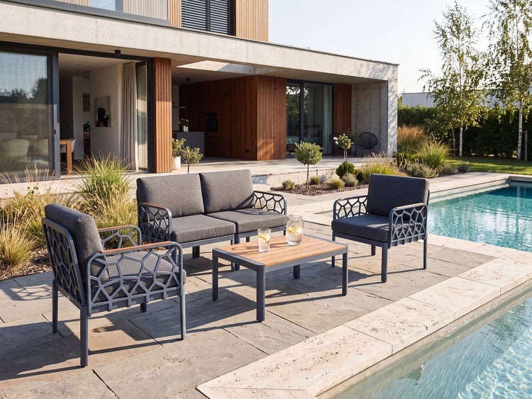 Moderne Loungegruppe mit Sofa, zwei Sesseln und Couchtisch auf einer Steinterrasse am Pool eines modernen Hauses.