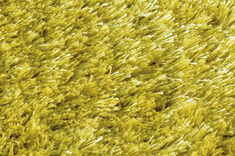 Nahaufnahme eines gelben Hochflor-Teppichs mit zotteliger Struktur.