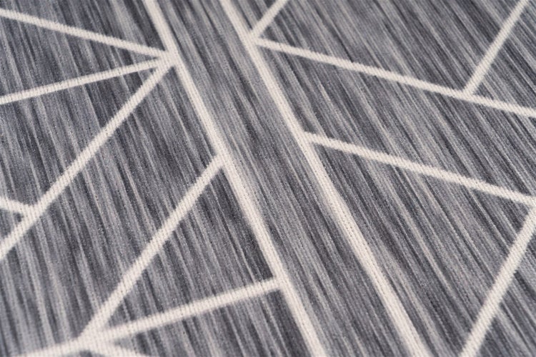Nahaufnahme eines gewebten Teppichs mit geometrischem Linienmuster und strukturierter Oberfläche.