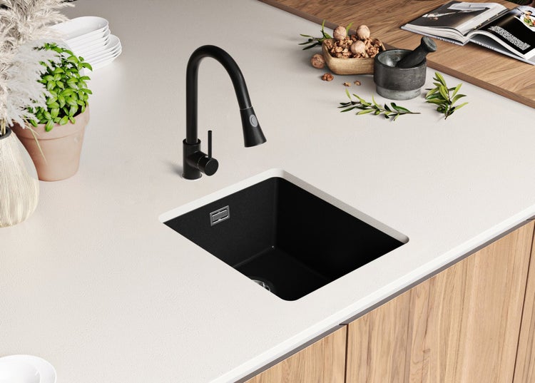 Schwarze Küchenspüle mit Wasserhahn auf einer hellen Arbeitsplatte